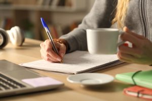 Woman writing near computer