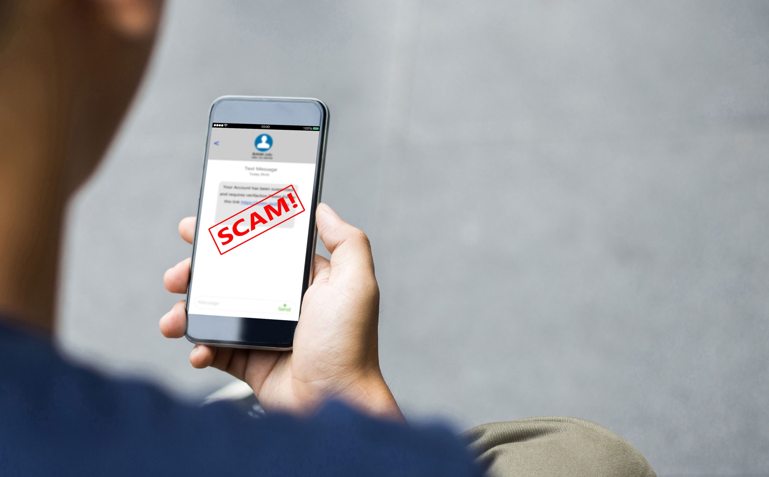 Hands holding a smart phone showing a Facebook message with the word Scam written across the screen