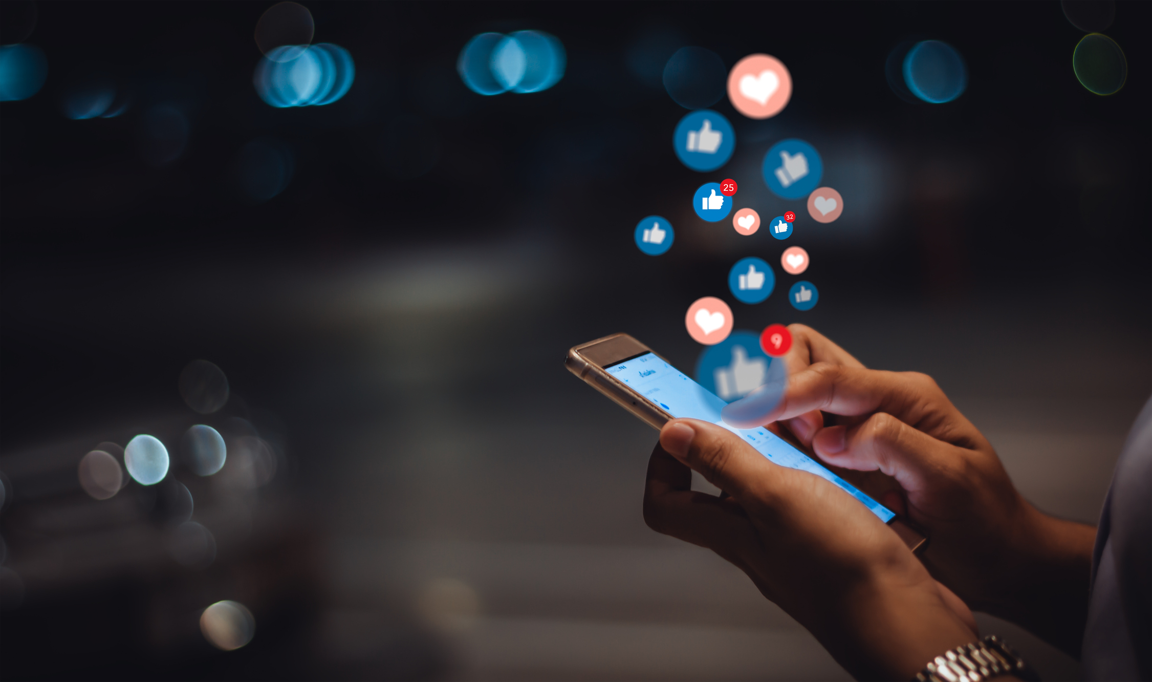 person holding phone with engagement bubbles from social media hovering above it